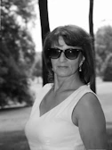 Teacher with short hair and a confident look, standing outdoors.