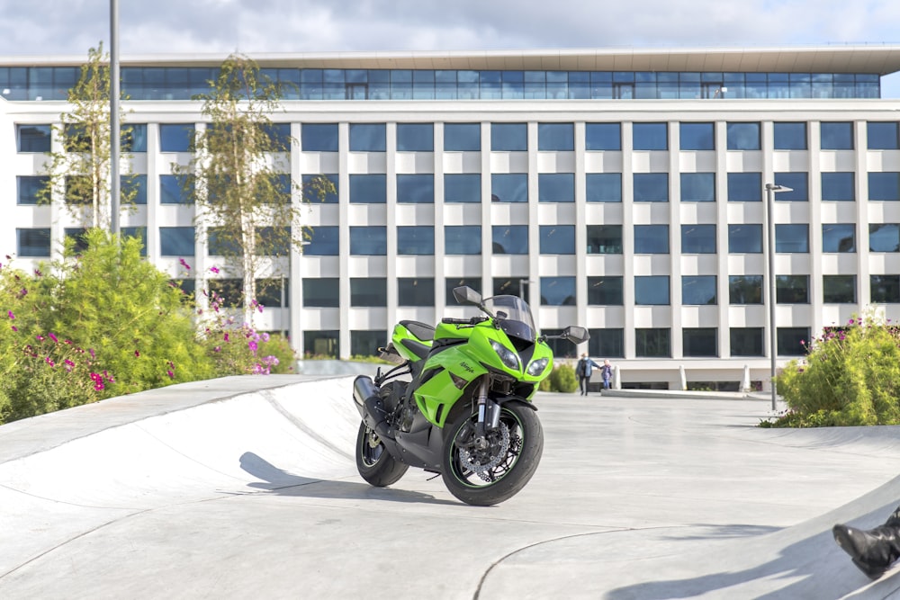 green and black sports bike parked near white concrete building during daytime