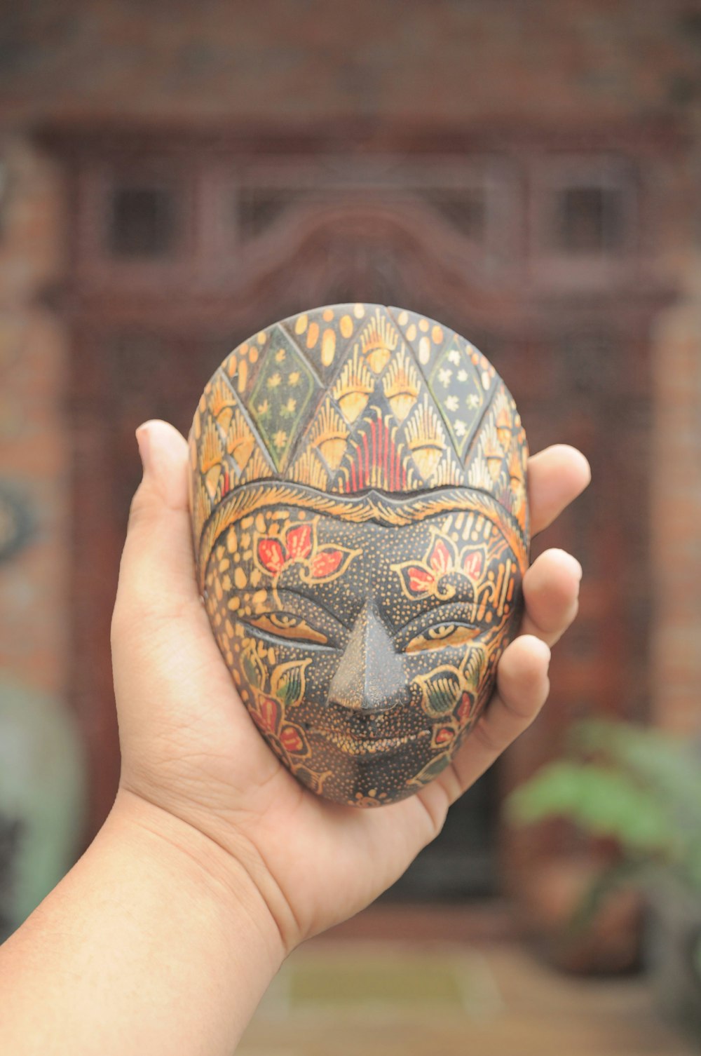 person holding gold mask figurine