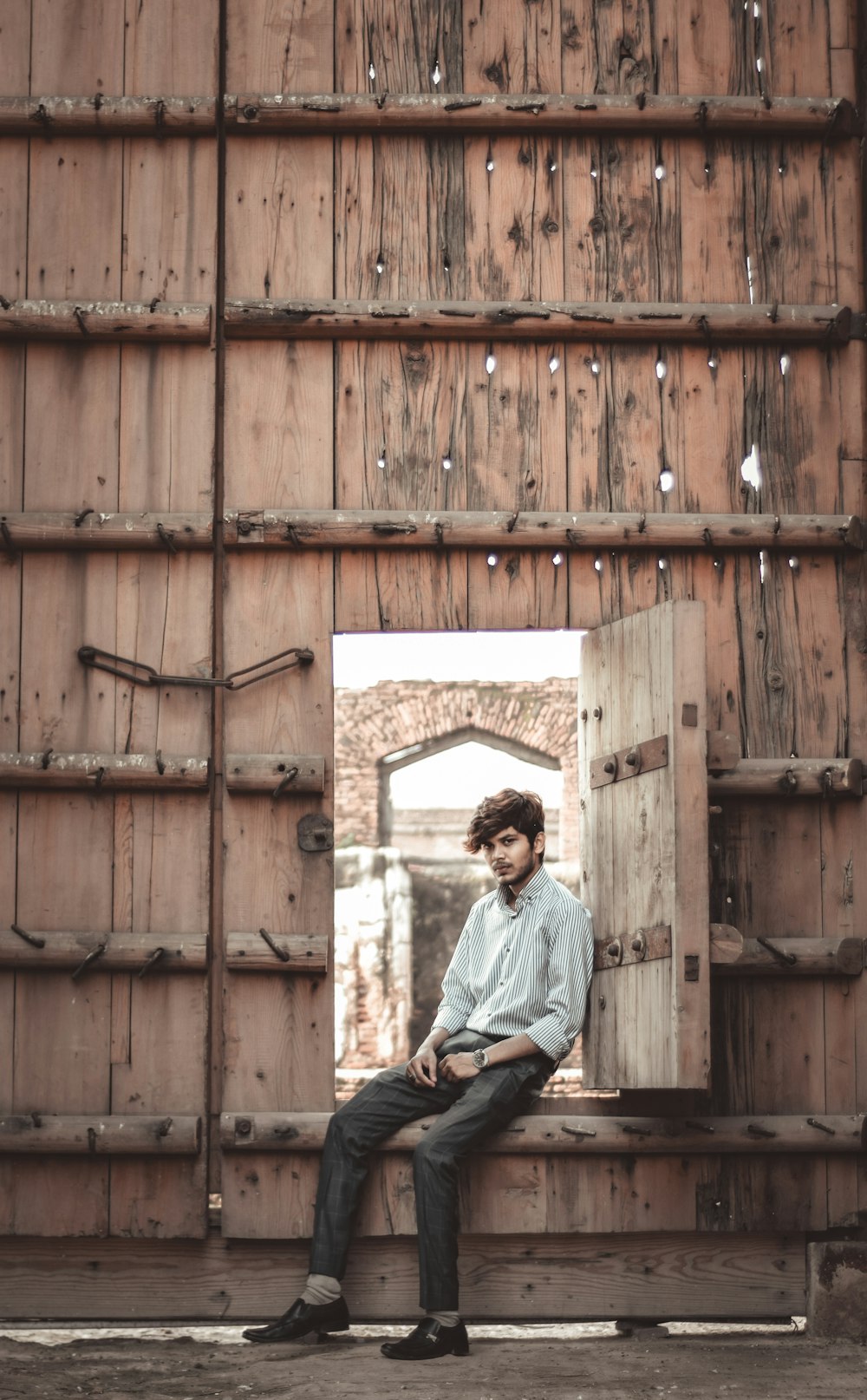 man in blue dress shirt sitting on brown wooden bench