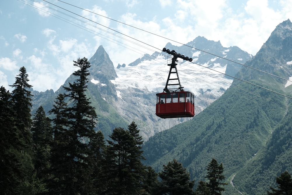 red cable car over green pine trees during daytime