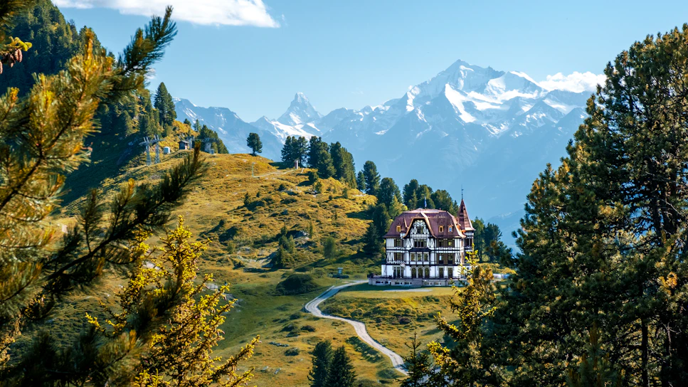 A stunning luxury villa perched on a hillside overlooking misty Himalayan peaks at sunrise.