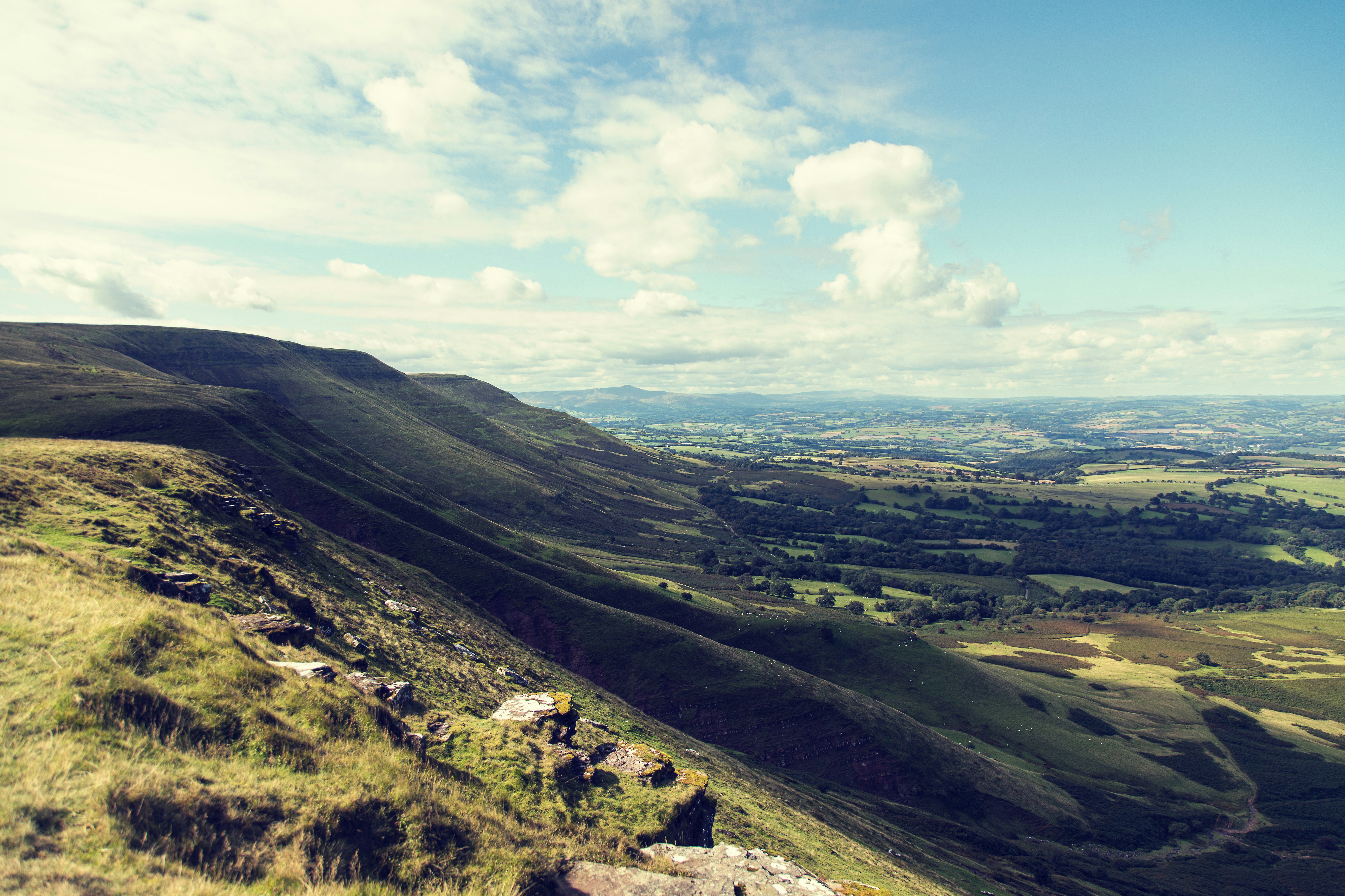 green grass field on mountain under blue sky during daytime