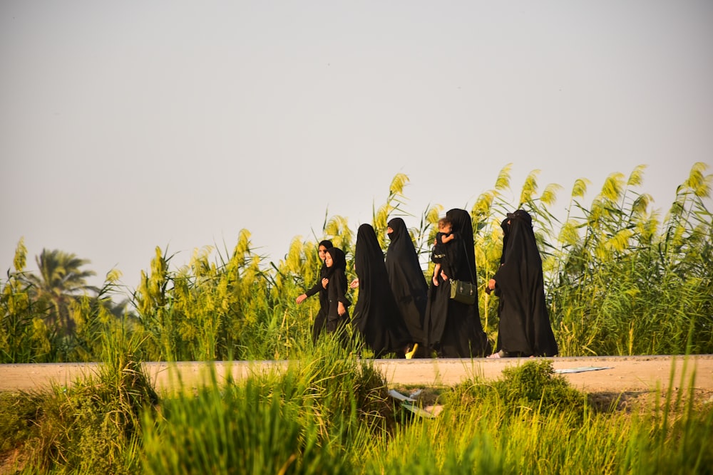 man and woman in black dress standing on green grass field during daytime