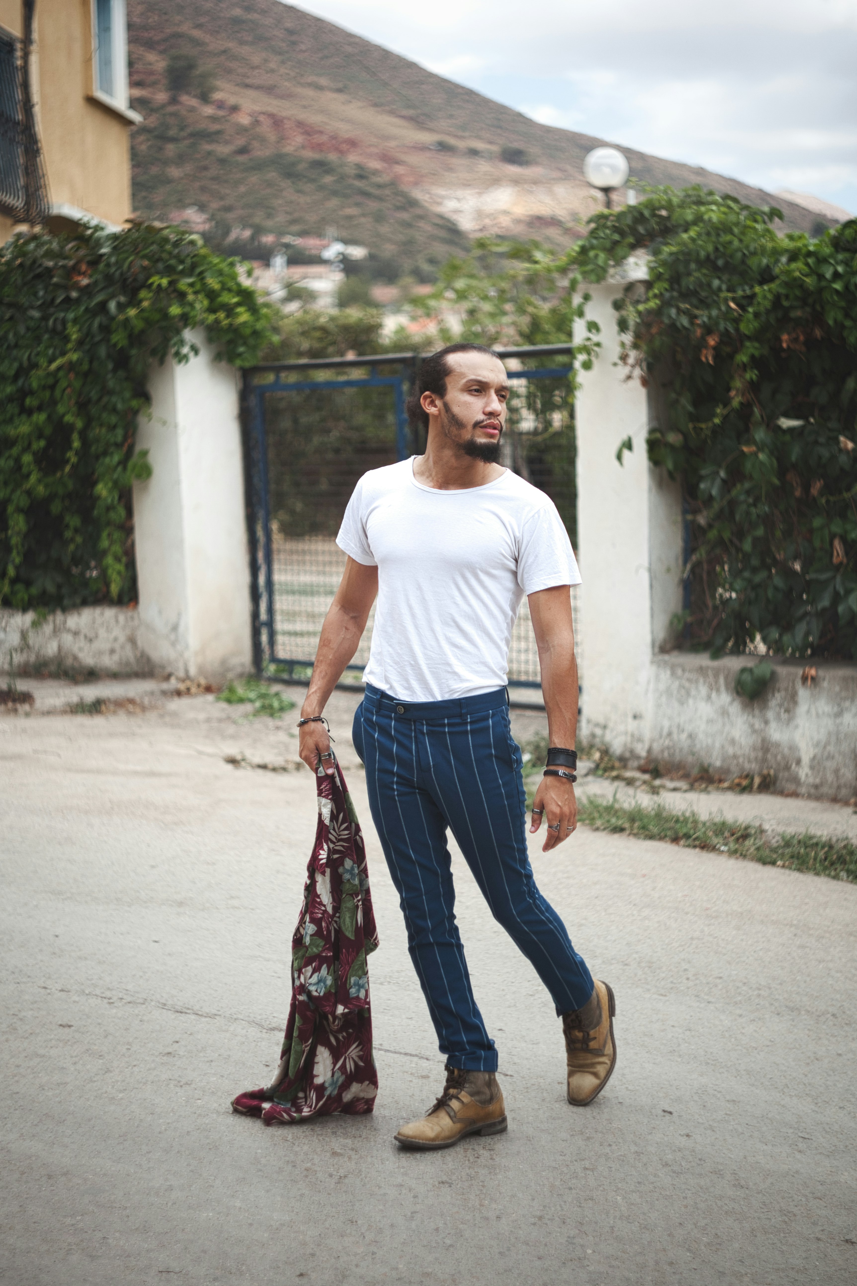 man in white crew neck t-shirt and blue denim jeans holding red and black floral