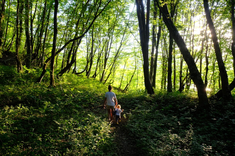 Homme en T-shirt blanc et jean bleu marchant sur le champ d’herbe verte pendant la journée