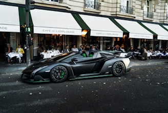 A modern white sedan with clean lines parked in front of a classic European cafe
