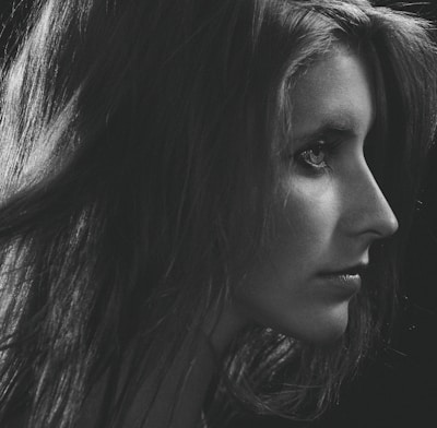 Elegant side profile showing long, voluminous black extensions styled in loose waves.