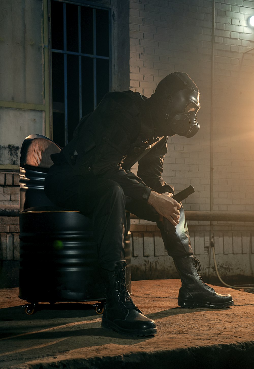 man in black jacket and pants sitting on black plastic drum