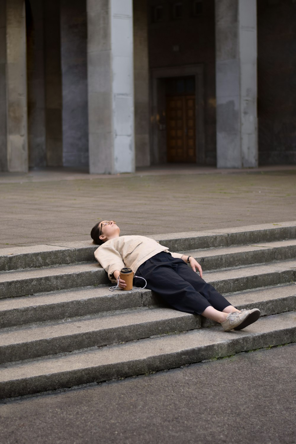 man in brown hoodie and black pants sitting on gray concrete stairs