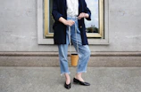 A trendy handbag styled with casual denim and a crisp white tee on a sidewalk.