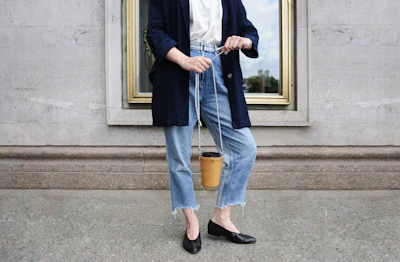 A trendy handbag styled with casual denim and a crisp white tee on a sidewalk.