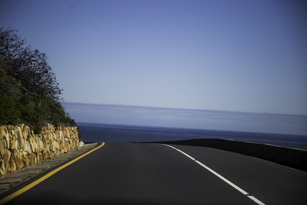 gray concrete road near body of water during daytime