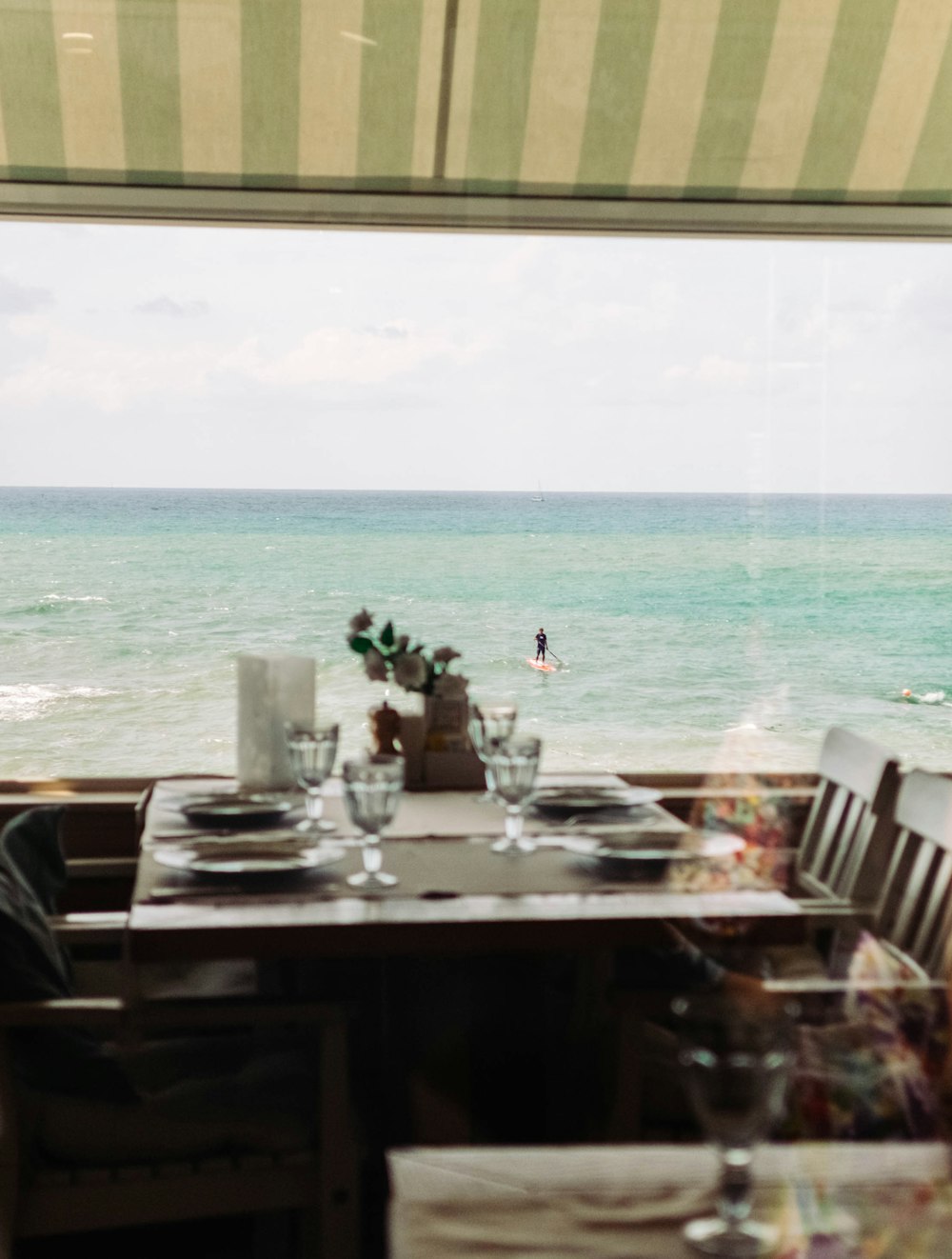 brown wooden table and chairs near sea during daytime