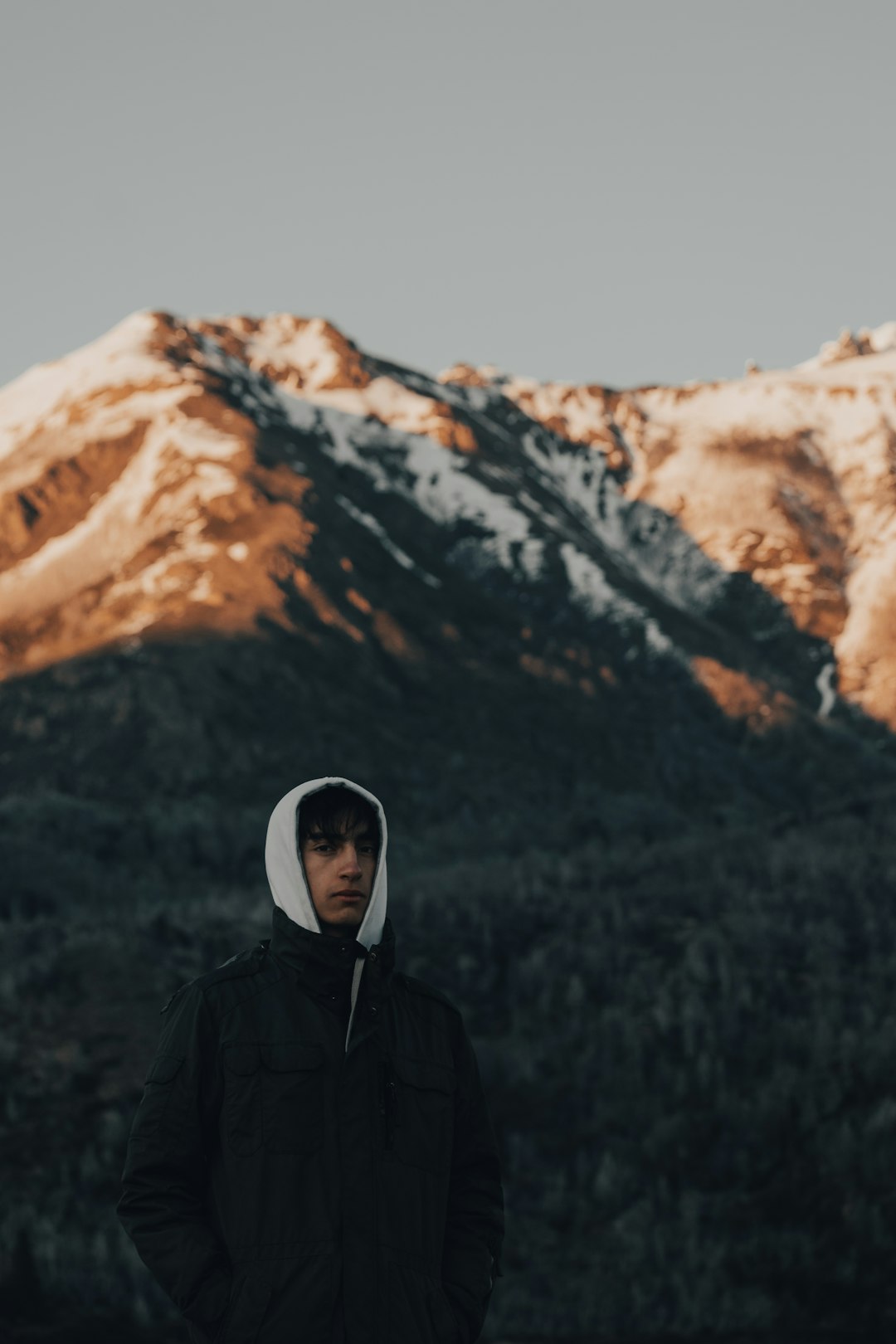 man in black jacket standing near brown mountain during daytime
