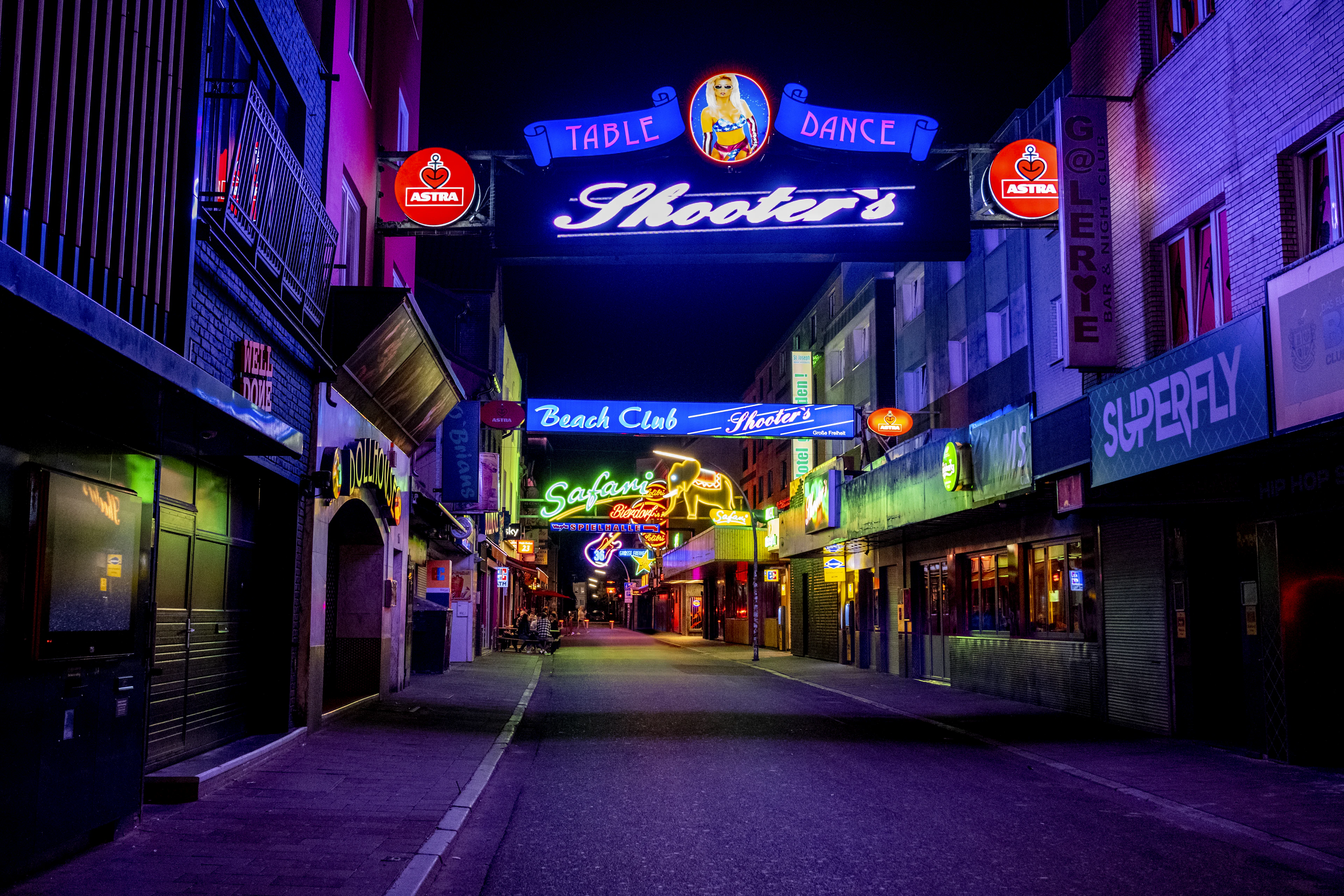 The neon signs of Grosse Freiheit off the Reeperbahn in Hamburg's St. Pauli glowing pink, blue and green over an empty late-night street, Astra beer roundels flanking a lit marquee