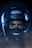 A close-up view of a person wearing a motorcycle helmet, with only their eyes visible. The helmet is black with a glossy finish and the brand name 'Shoei' printed on the front. The lighting is dramatic with a blue hue, enhancing the intense gaze of the person's eyes.
