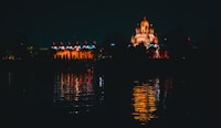 people walking on sidewalk near body of water during night time