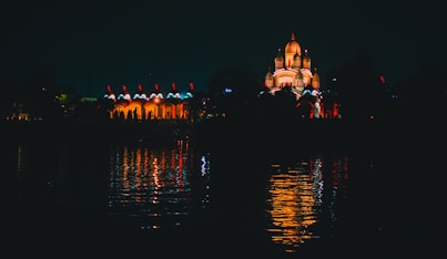 people walking on sidewalk near body of water during night time