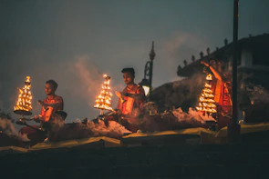 Priests performing a sacred puja with flickering diyas illuminating their faces.