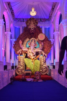 gold hindu deity statue on purple couch