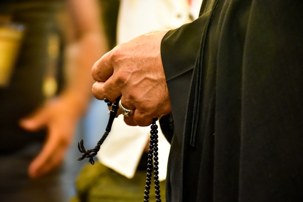 A close-up of hands holding rosary beads during a community prayer session.
