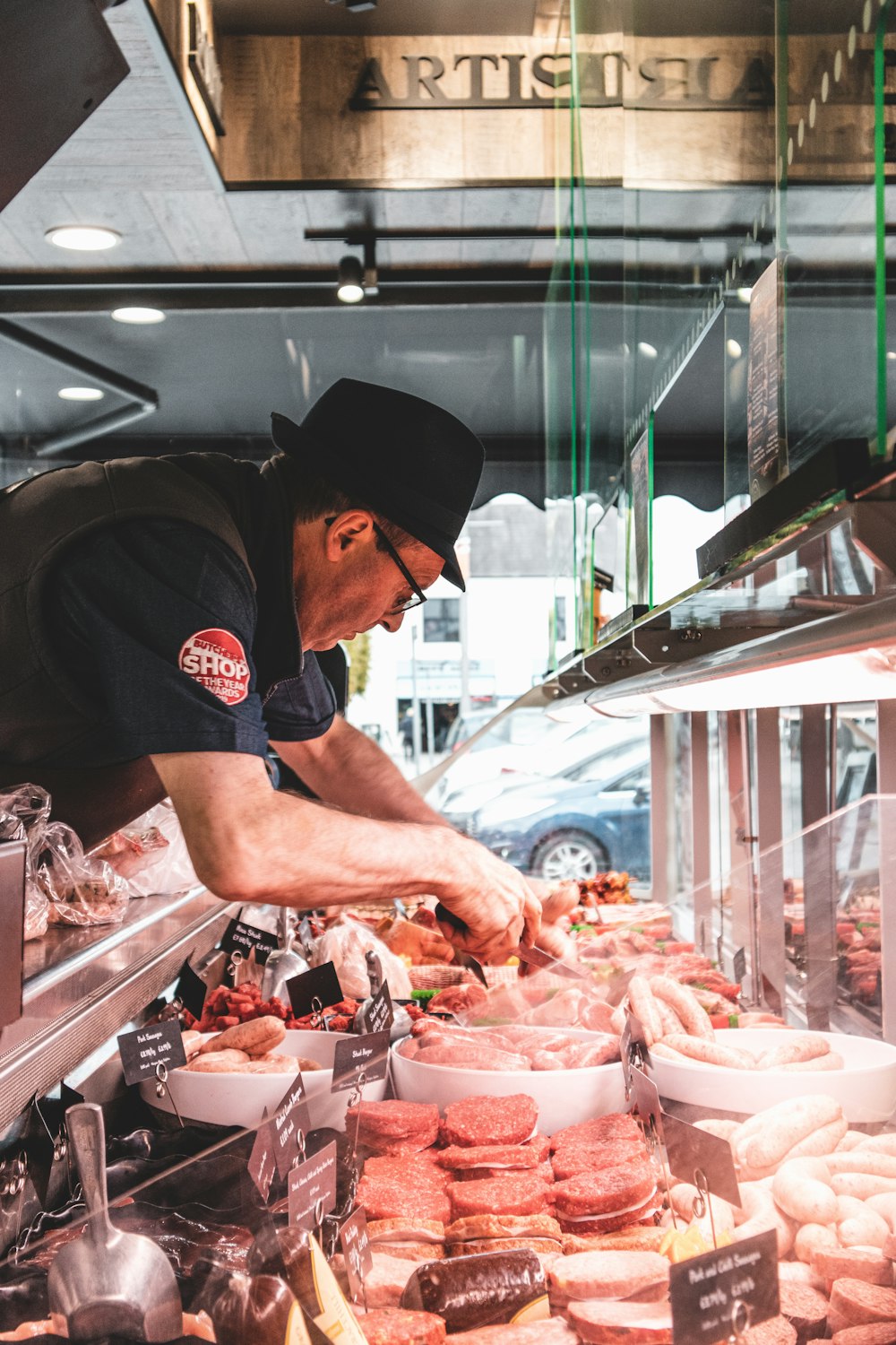 Mann in schwarzem Rundhals-T-Shirt und schwarzem Hut vor rohem Fleisch