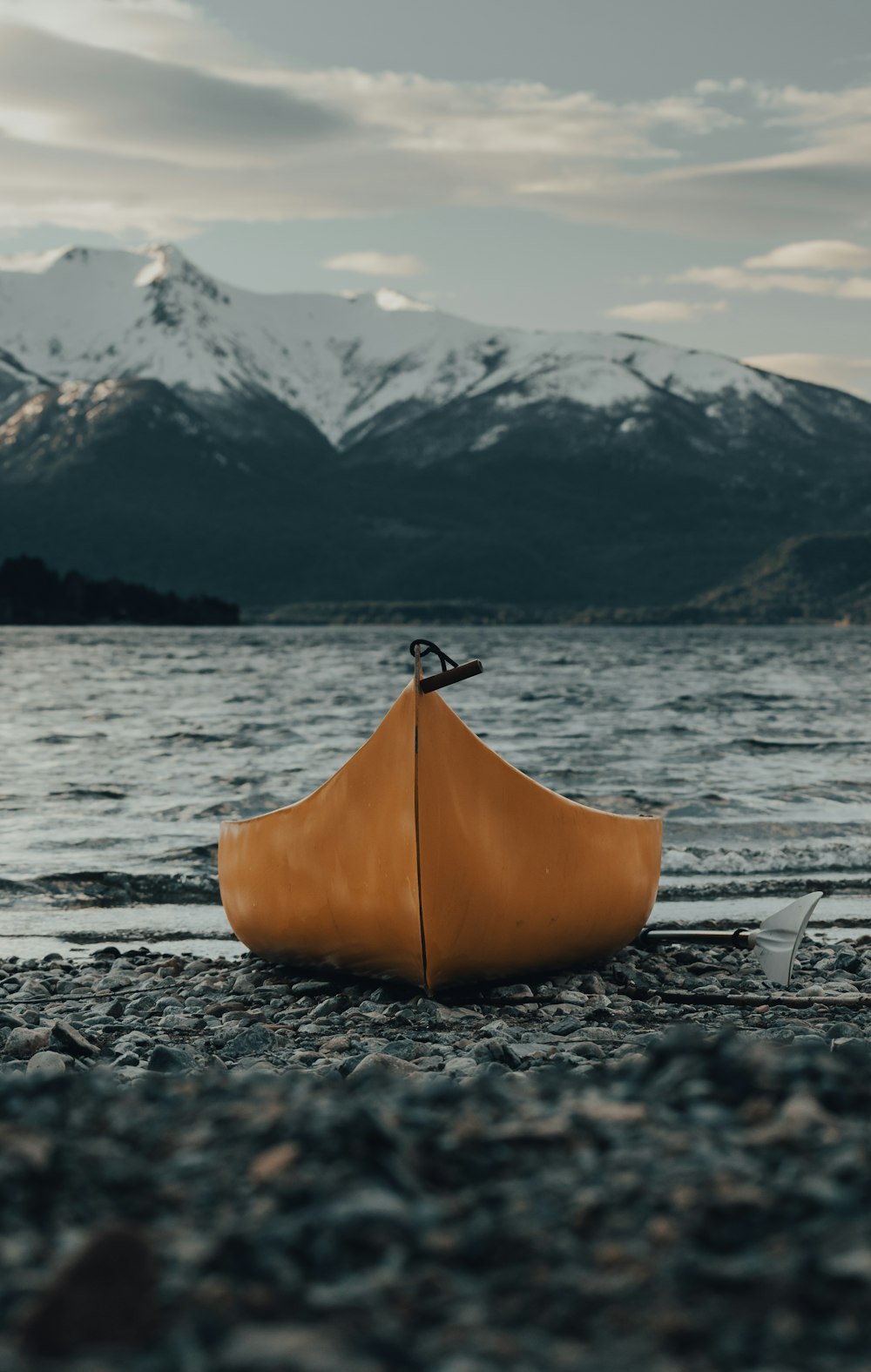 orange kayak on gray sand near body of water during daytime