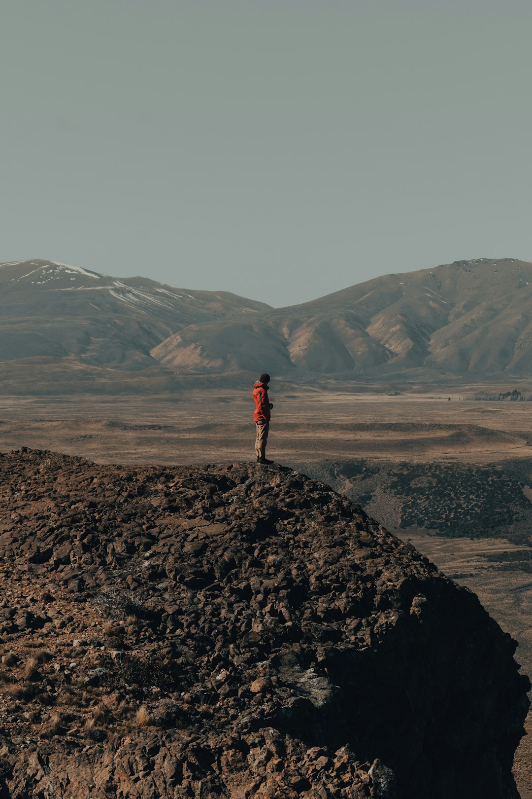 person in red jacket standing on rock formation during daytime