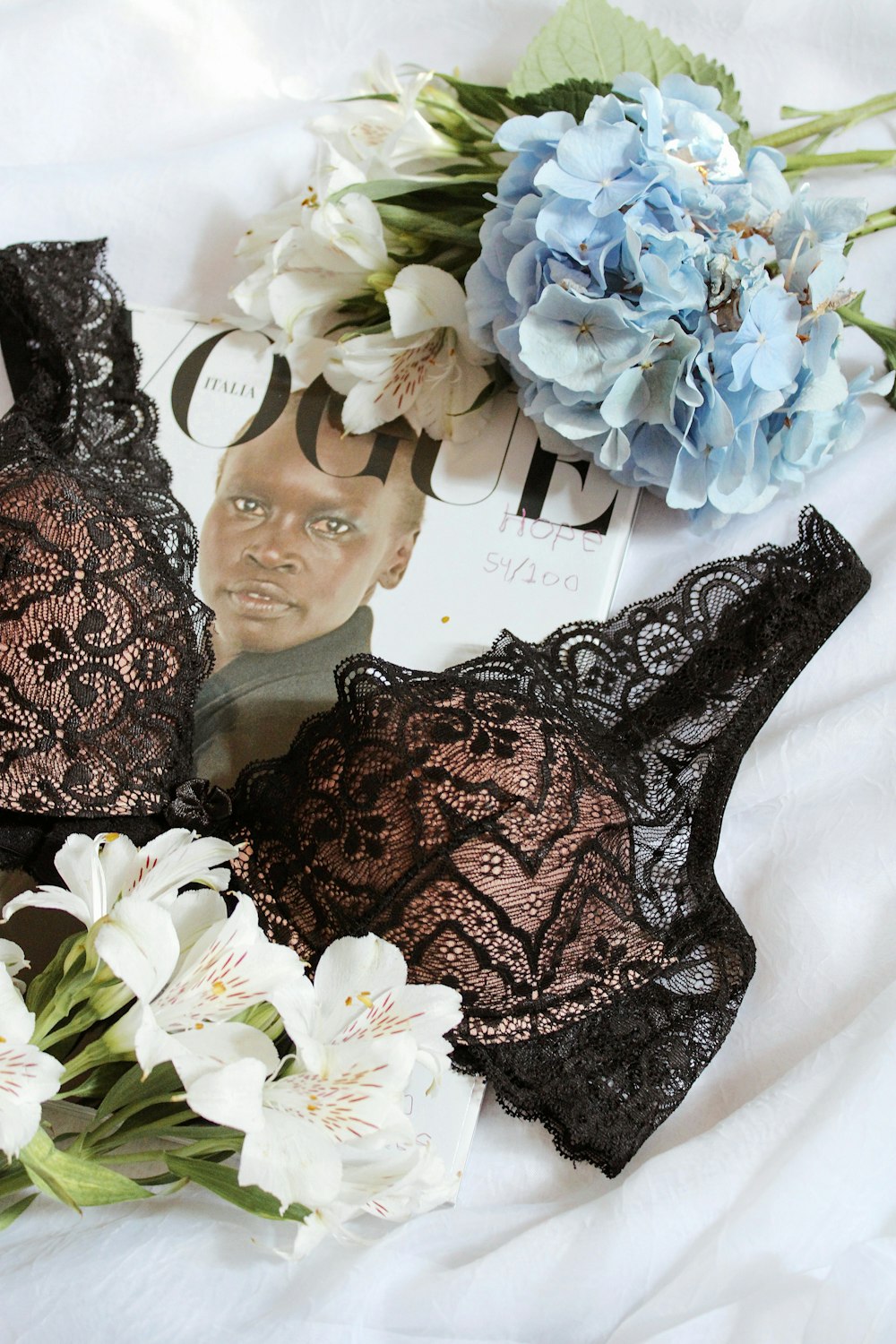 black lace brassiere beside white and purple flowers