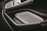 Close-up of a sleek car door panel with premium speaker upgrades and ambient blue lighting.