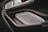 A close-up view of an interior car door panel featuring modern and sleek design elements. The panel includes a metallic speaker grille, an electronic lock control, and stitched leather detailing, suggesting luxury and technological advancement.
