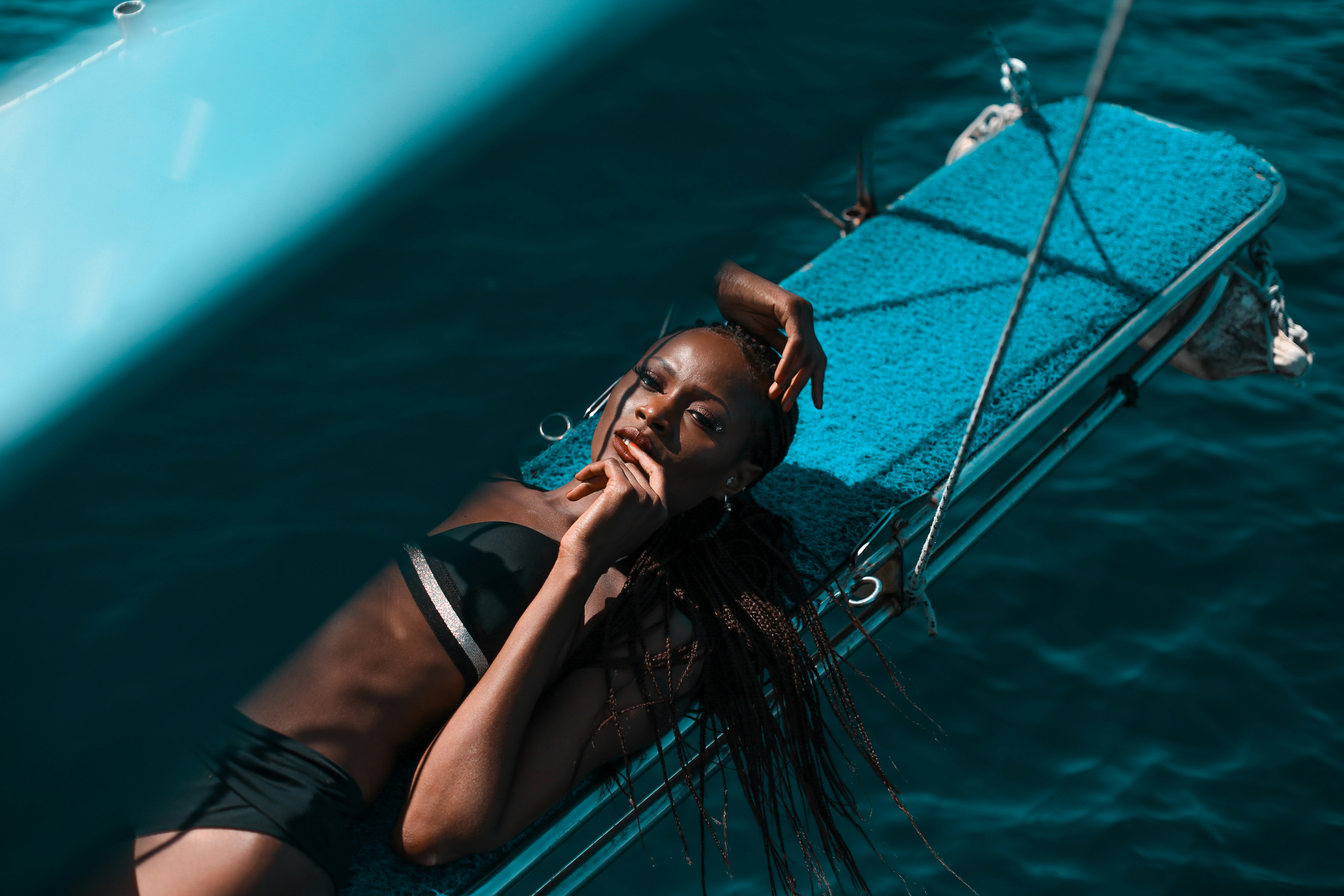 woman in black bikini lying on blue and white boat during daytime