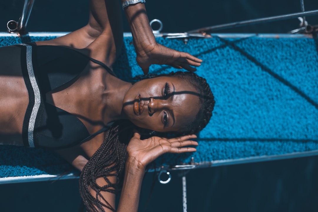 woman in black brassiere lying on blue hammock