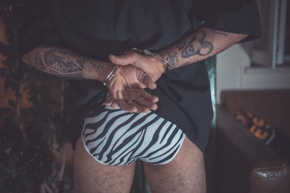 homme en short rayé noir et blanc avec tatouage noir sur le bras droit