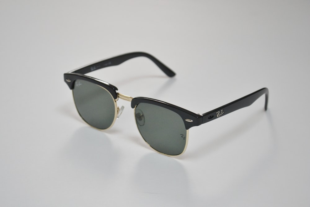 gafas de sol con montura negra sobre superficie blanca