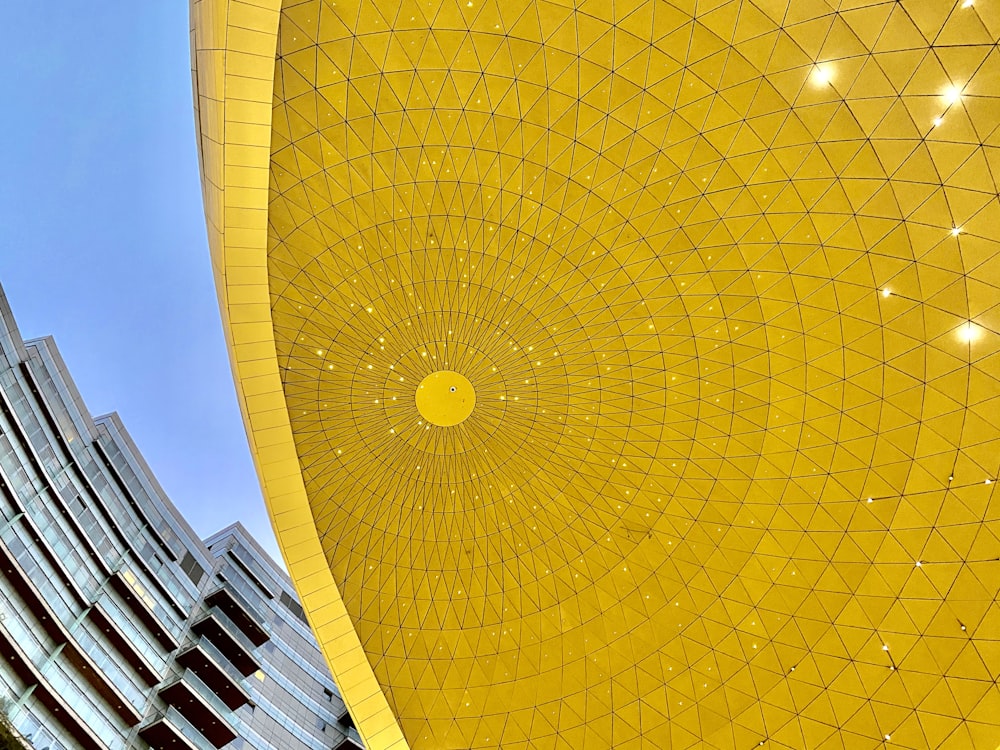 日中の青空の下で黄色い太陽の形をした構造物