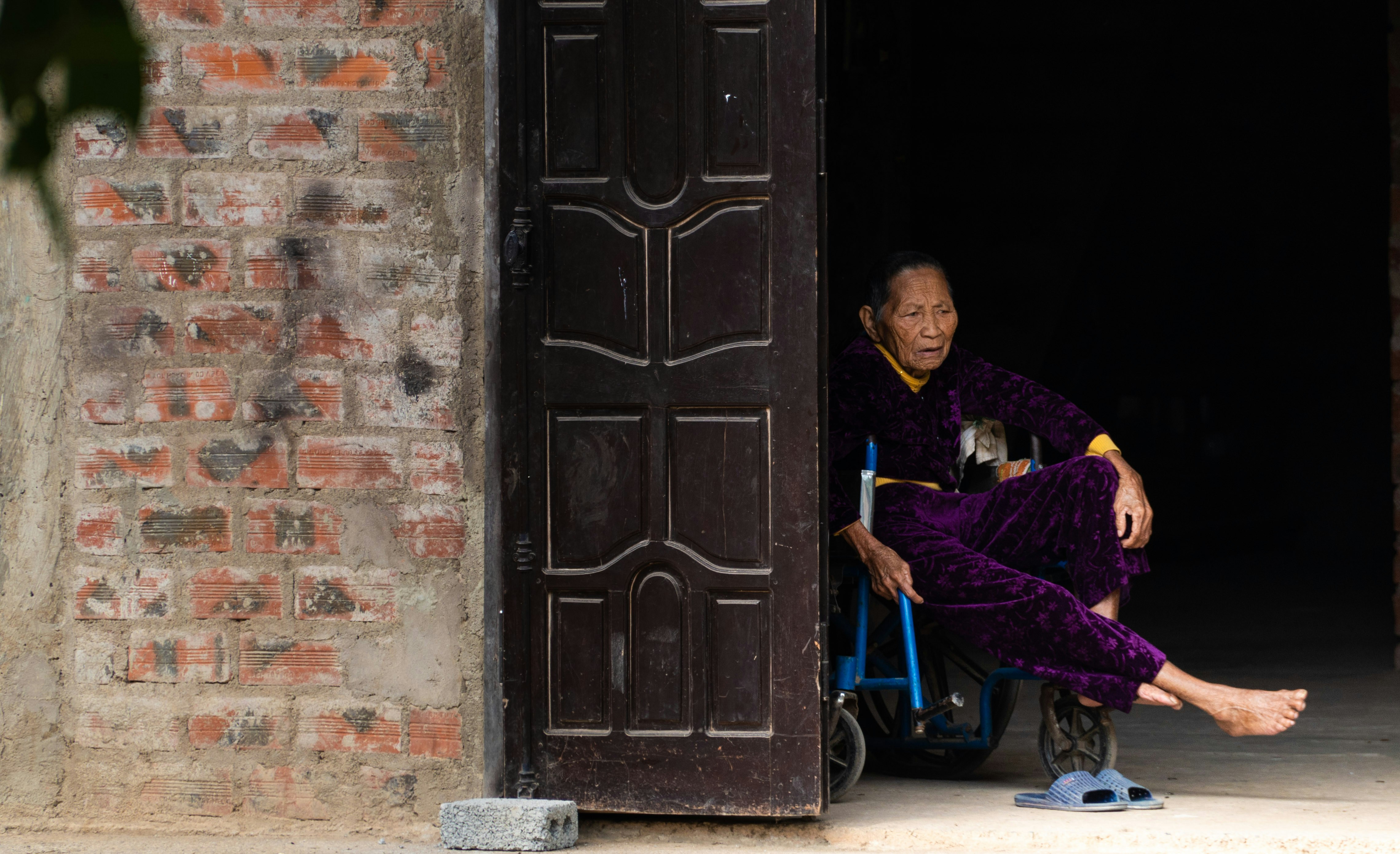 woman in purple robe sitting on blue chair near brown wooden door