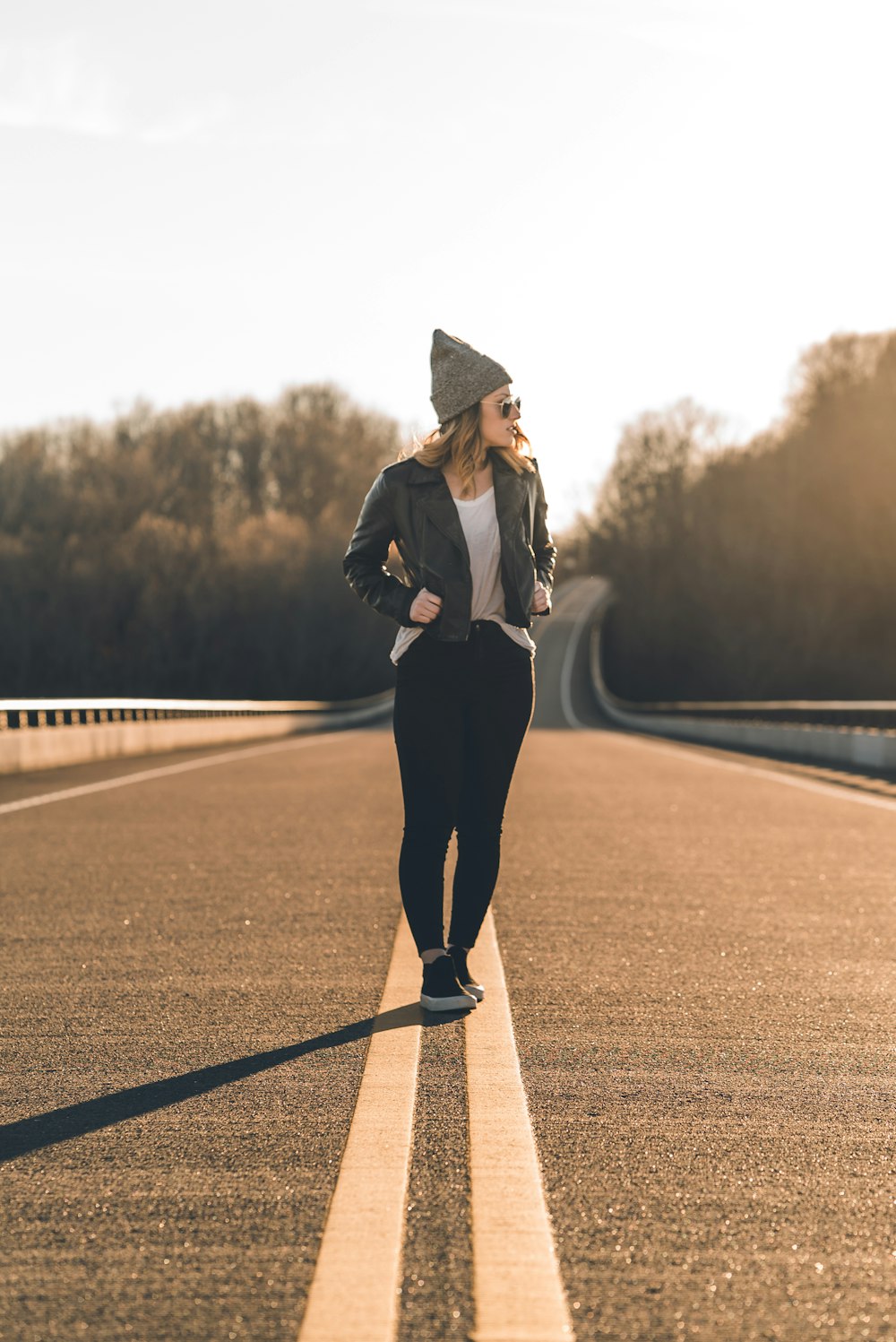 woman in black coat and black pants standing on road during daytime