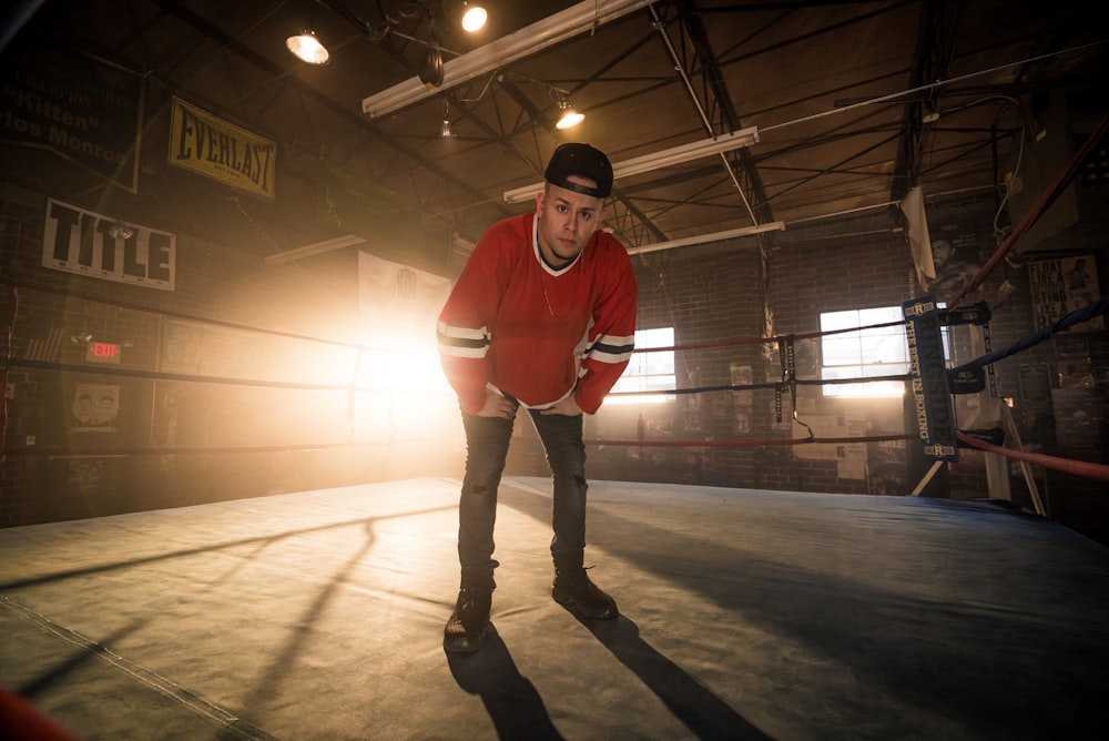 man in red crew neck t-shirt and black pants standing on brown floor