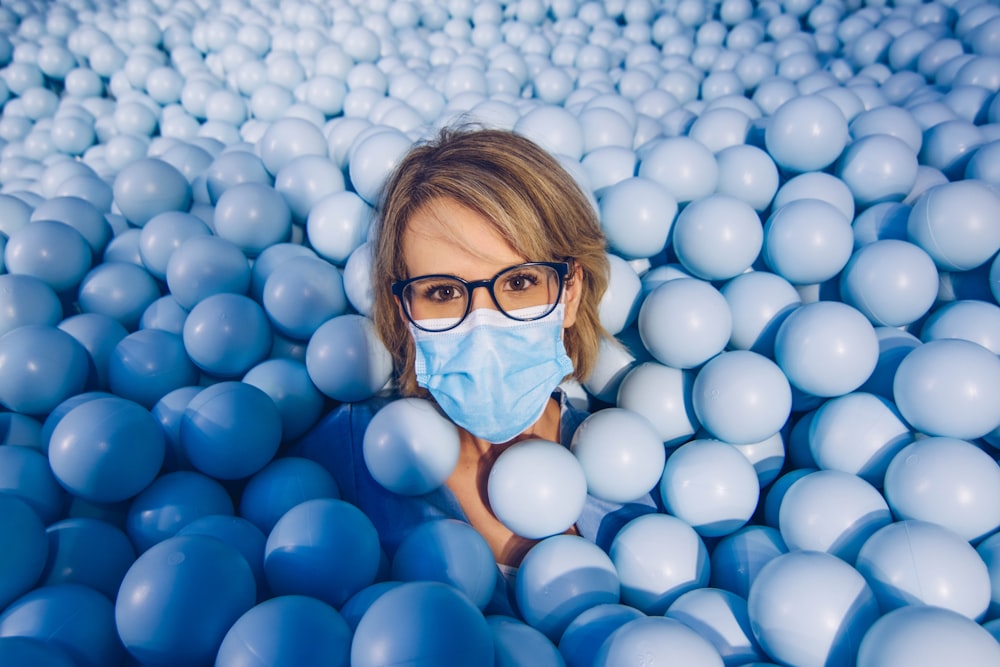 girl in blue framed eyeglasses and blue shirt on white balloons