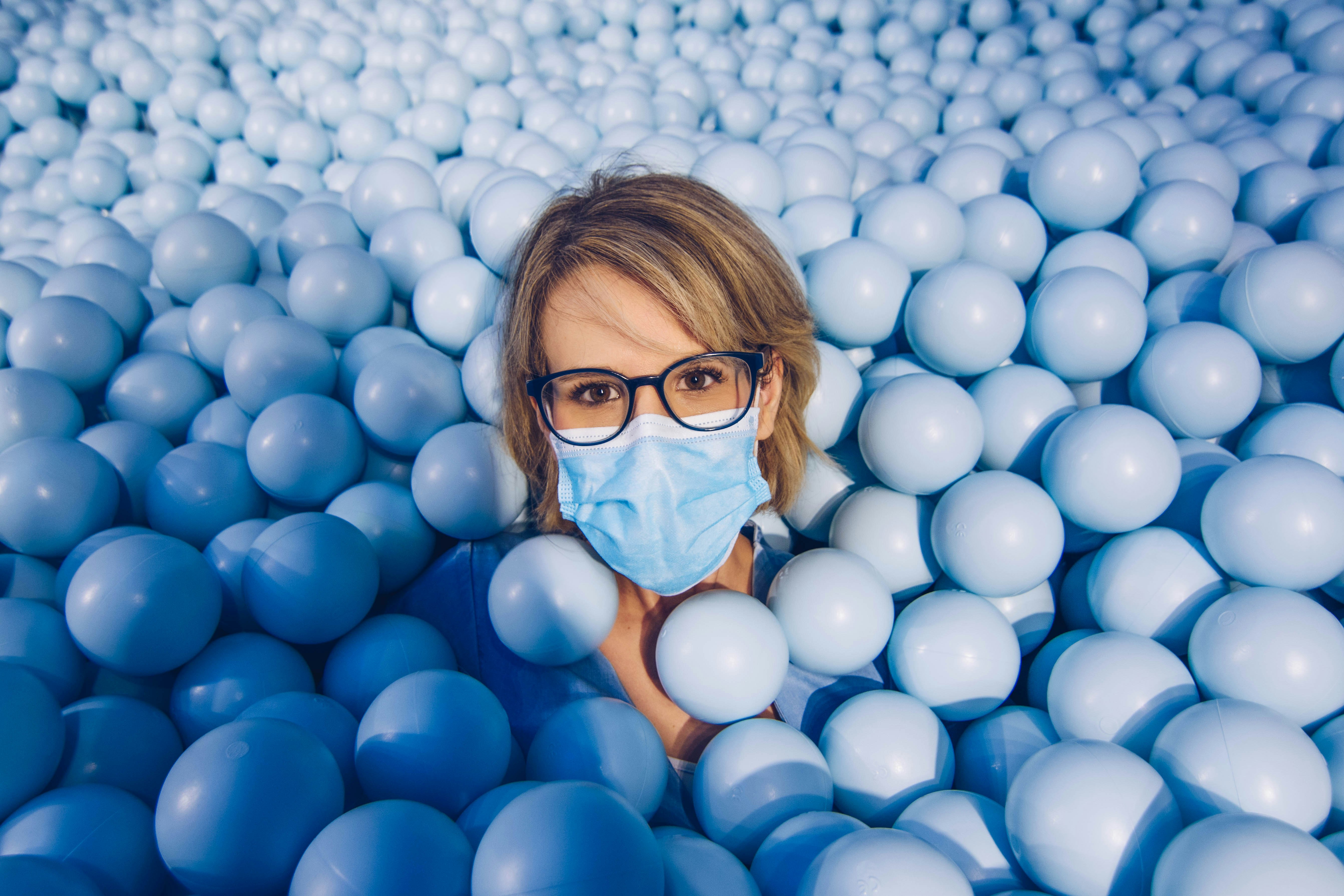 girl in blue framed eyeglasses and blue shirt on white balloons