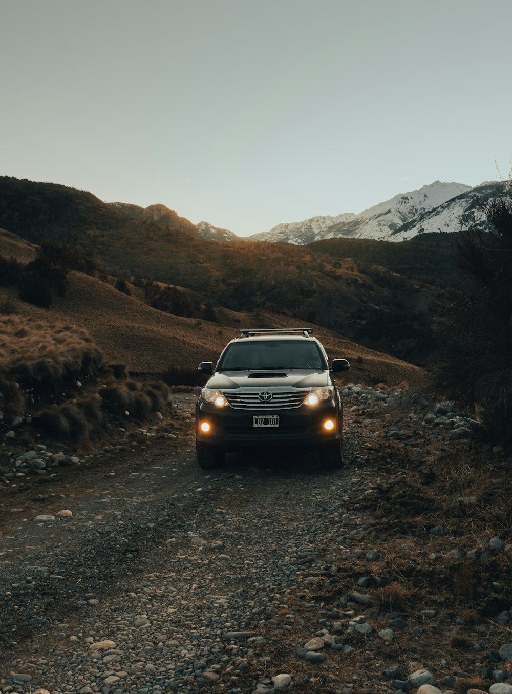 昼間、山の近くの道路を走る黒い車