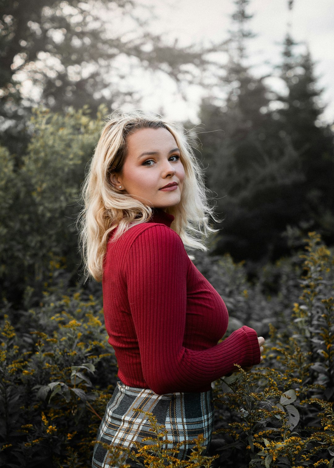 woman in red long sleeve shirt standing near green trees during daytime