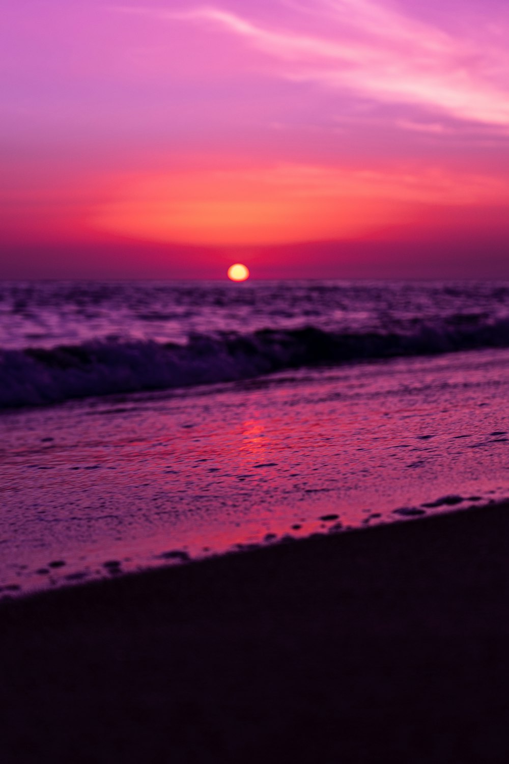 sea waves crashing on shore during sunset