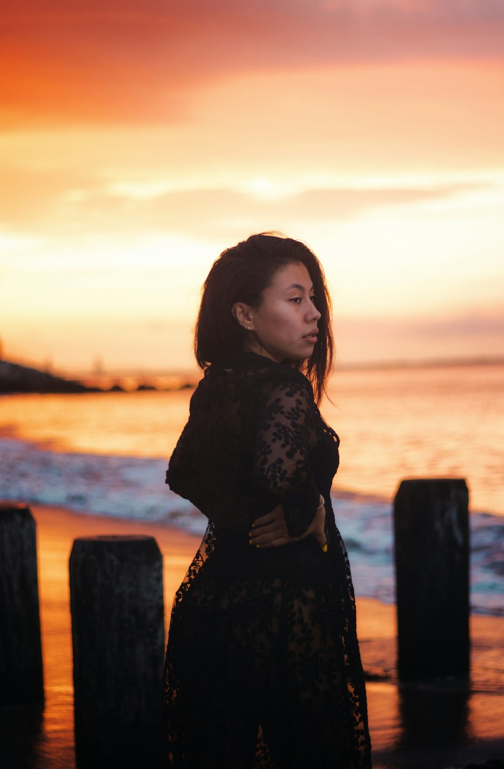 woman in black long sleeve dress standing on brown wooden fence during daytime