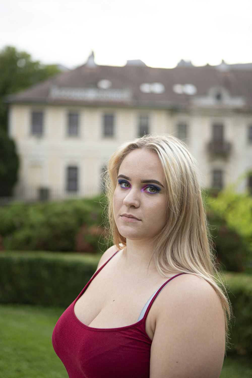 femme en débardeur blanc debout près du champ d’herbe verte pendant la journée