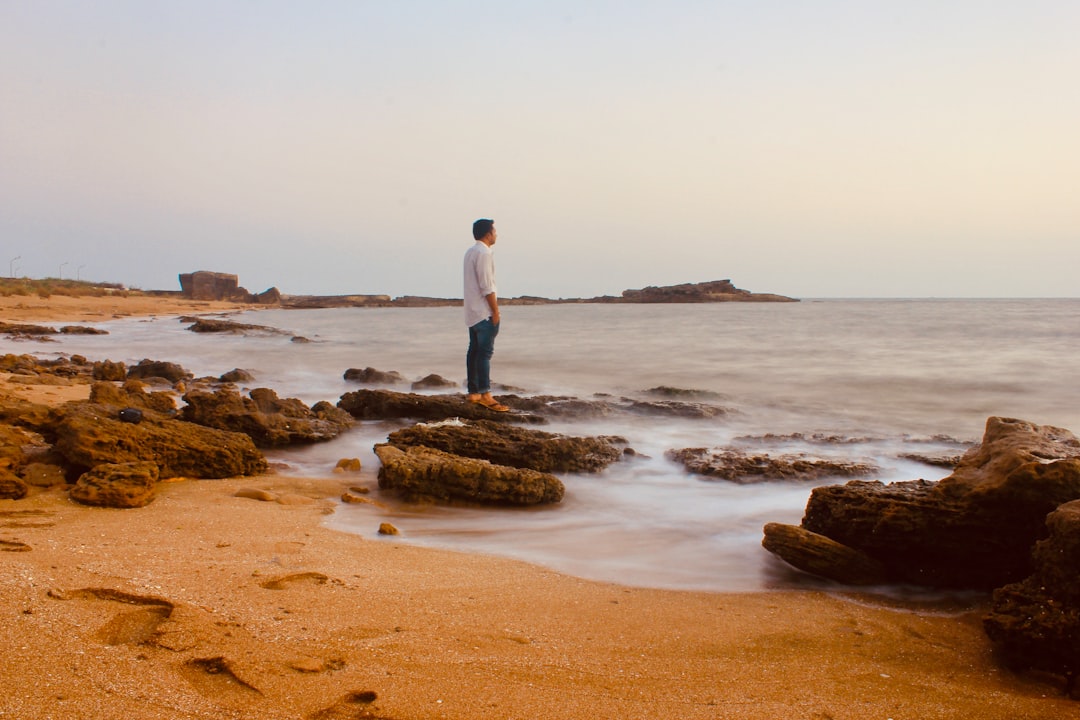 man standing at shore alone on rocks