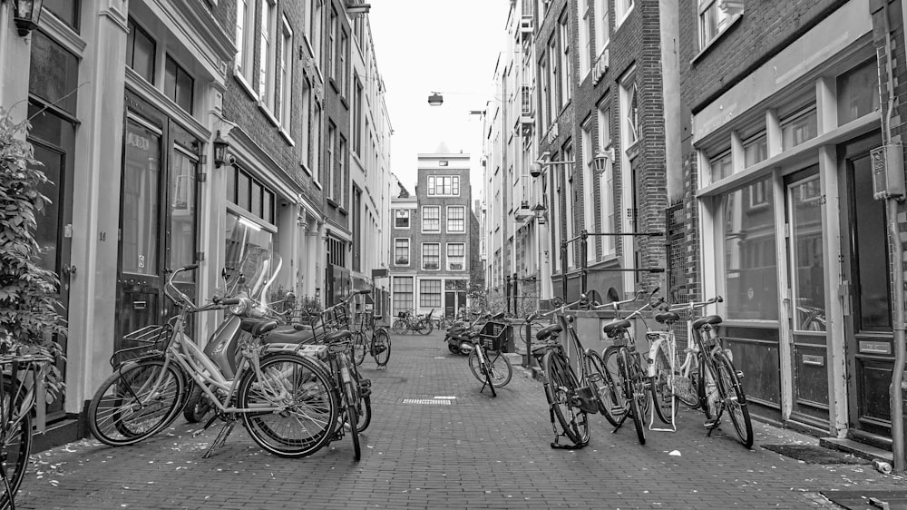 grayscale photo of bicycles parked on sidewalk