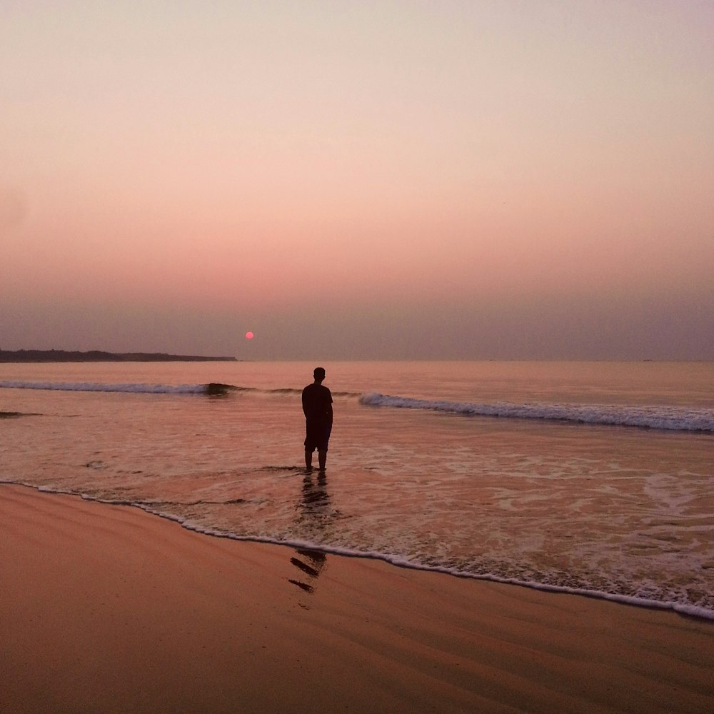 2 people walking on beach during sunset